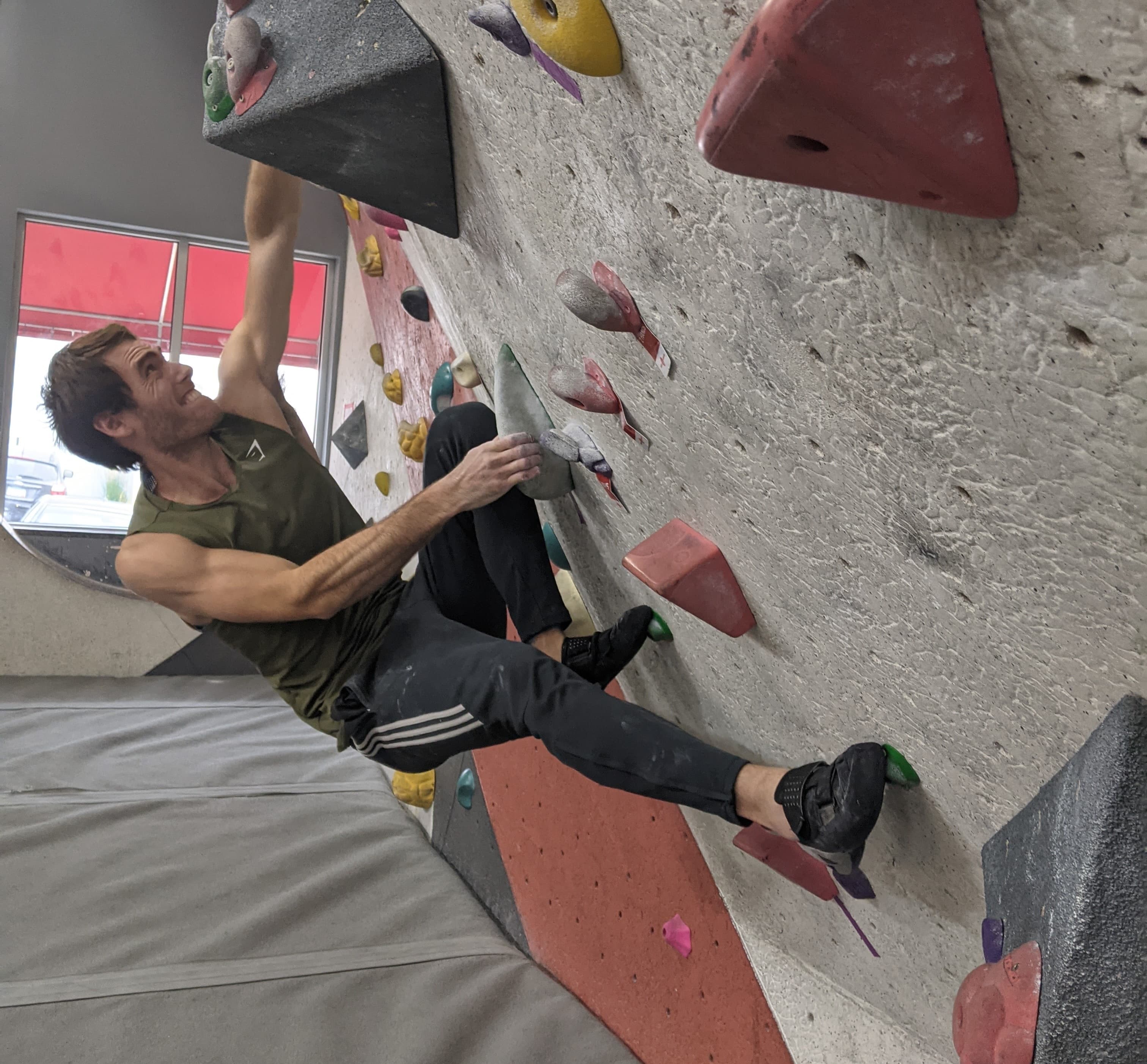 Climbing an artificial boulder problem at an indoor rock climbing facility
